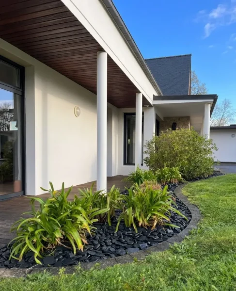Vue d'ensemble d'un jardin contemporain à Pontivy après l'intervention : minéraux propres, pelouse tondue et végétaux sculptés.