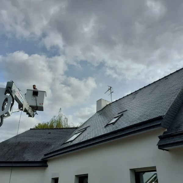 Vue d'ensemble d'une maison en pierre avec toiture en ardoise et camion nacelle en intervention à Lamballe
