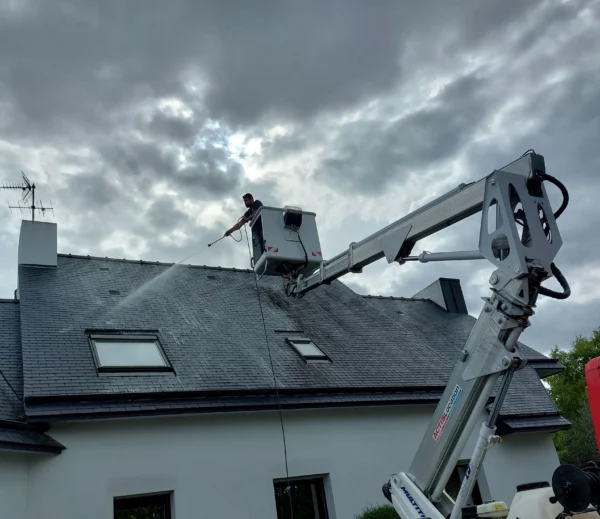 Technicien Tardivel Paysage nettoyant à haute pression une toiture en ardoise à Lamballe depuis un camion nacelle