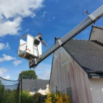Technicien Tardivel Paysage appliquant un traitement anti-mousse sur une façade à Ploufragan depuis une nacelle