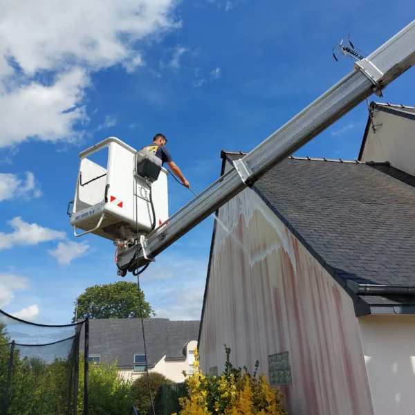 Technicien Tardivel Paysage appliquant un traitement anti-mousse sur une façade à Ploufragan depuis une nacelle